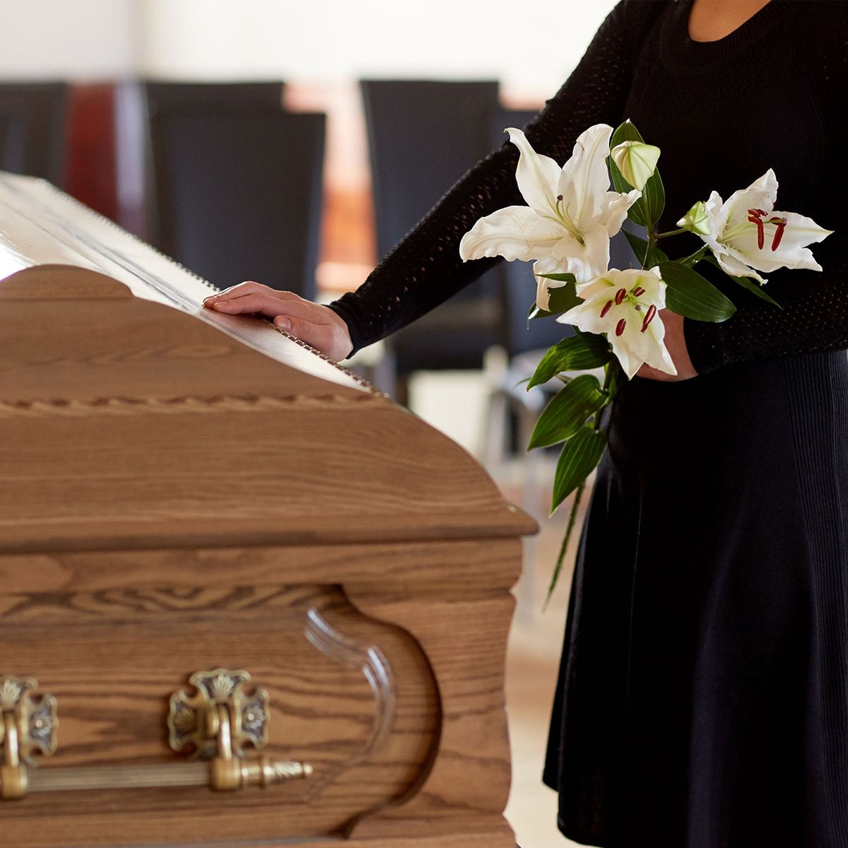Frau mit weißen Blumen berührt den Sarg