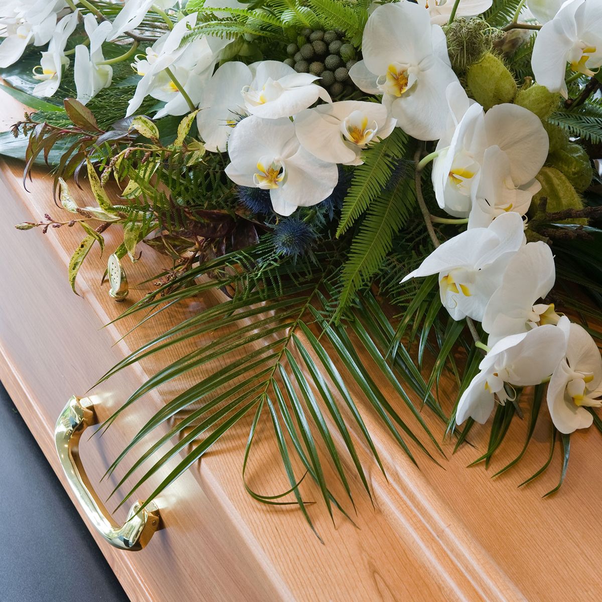 Ein Sarg aus Holz mit weißen Blumen