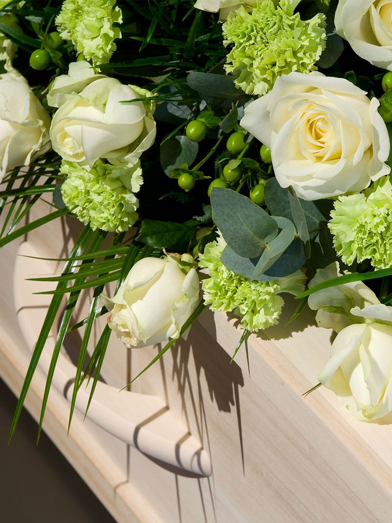 Nahaufnahme eines Sarges mit weißen Rosen